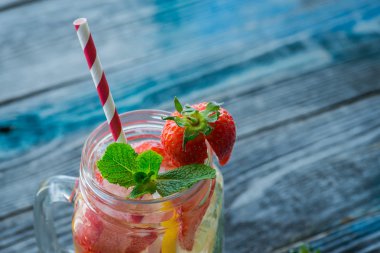 Limon ve çilek infüzyon su bir rustik ahşap yüzeyde ile sürahi