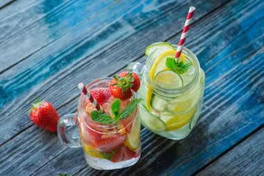 Bir rustik ahşap yüzeyde su testileri limon, kireç ve çilek ile infüzyon