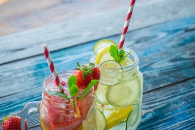 Bir rustik ahşap yüzeyde su testileri limon, kireç ve çilek ile infüzyon