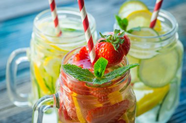Testi ile limon, limon, çilek ve salatalık su bir rustik ahşap yüzey üzerinde infüzyon
