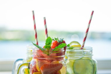 Testi ile limon, limon, çilek ve salatalık su bir rustik ahşap yüzey üzerinde infüzyon