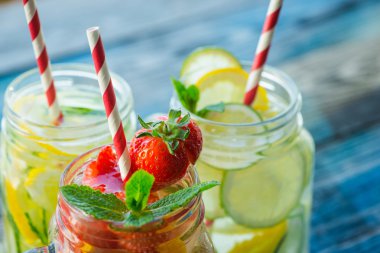 Testi ile limon, limon, çilek ve salatalık su bir rustik ahşap yüzey üzerinde infüzyon