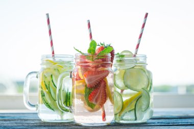 Testi ile limon, limon, çilek ve salatalık su bir rustik ahşap yüzey üzerinde infüzyon