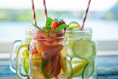 Testi ile limon, limon, çilek ve salatalık su bir rustik ahşap yüzey üzerinde infüzyon