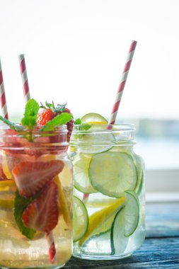 Testi ile limon, limon, çilek ve salatalık su bir rustik ahşap yüzey üzerinde infüzyon