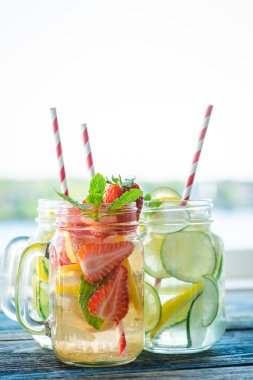 Testi ile limon, limon, çilek ve salatalık su bir rustik ahşap yüzey üzerinde infüzyon