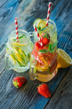 Testi ile limon, limon, çilek ve salatalık su bir rustik ahşap yüzey üzerinde infüzyon