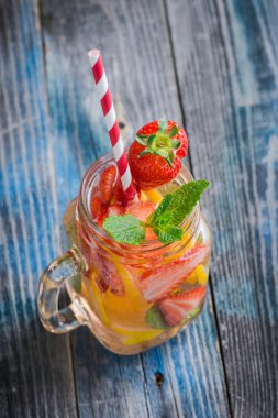 Limon ve çilek infüzyon su bir rustik ahşap yüzeyde ile sürahi