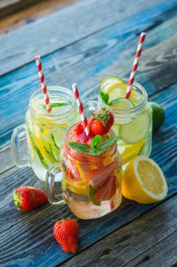 Testi ile limon, limon, çilek ve salatalık su bir rustik ahşap yüzey üzerinde infüzyon