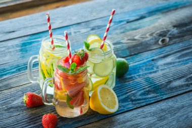 Testi ile limon, limon, çilek ve salatalık su bir rustik ahşap yüzey üzerinde infüzyon