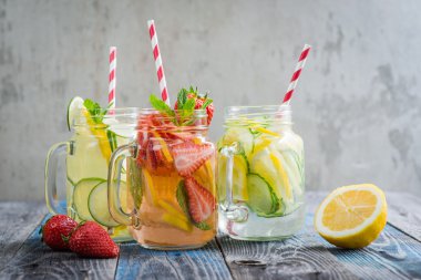 Testi ile limon, limon, çilek ve salatalık su bir rustik ahşap yüzey üzerinde infüzyon