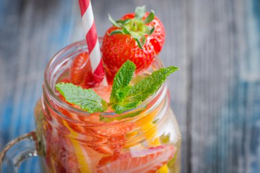 Limon ve çilek infüzyon su bir rustik ahşap yüzeyde ile sürahi