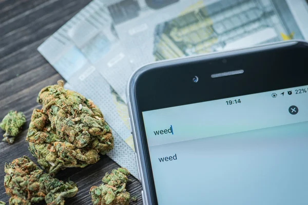 Phone, money and weed on a rustic wooden board