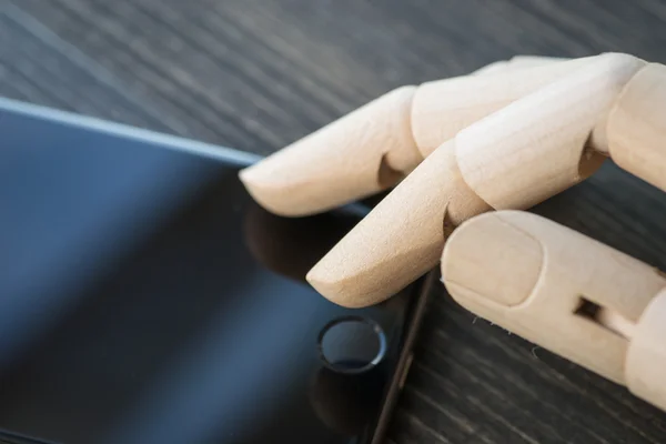 Artificial wooden hand with modern phone on wooden board — Stock Photo, Image