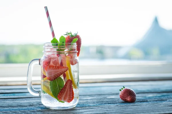 Krug mit Zitronen- und Erdbeerwasser auf rustikaler Holzoberfläche — Stockfoto