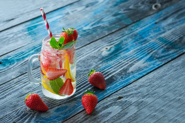 Krug mit Zitronen- und Erdbeerwasser auf rustikaler Holzoberfläche — Stockfoto