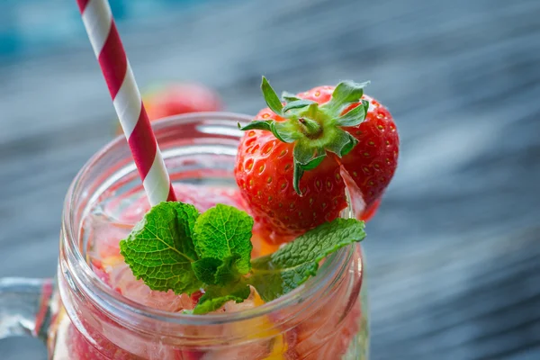 Jug dengan lemon dan air strawberry diresapi pada permukaan kayu pedesaan — Stok Foto