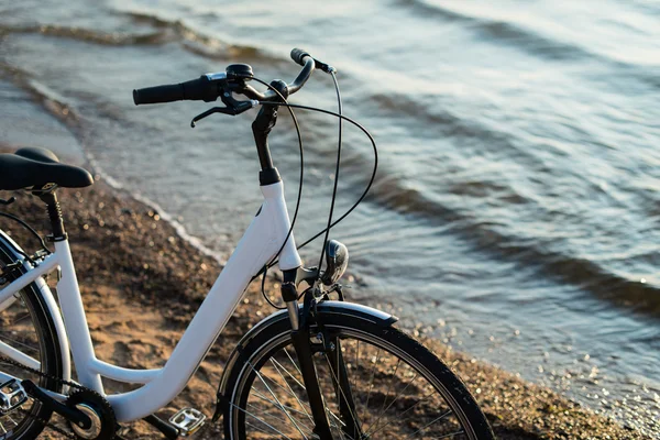 Bicicletta comfort bianca in spiaggia sotto un raggio di sole — Foto Stock