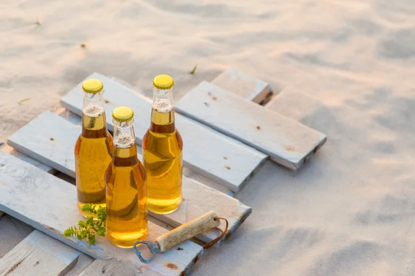 Trzy butelki piwa, stojąc na płycie rustykalne drewniane — Zdjęcie stockowe