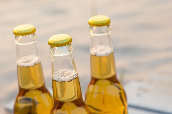 Rustik ahşap tahta üzerinde duran üç bira şişeleri — Stok fotoğraf