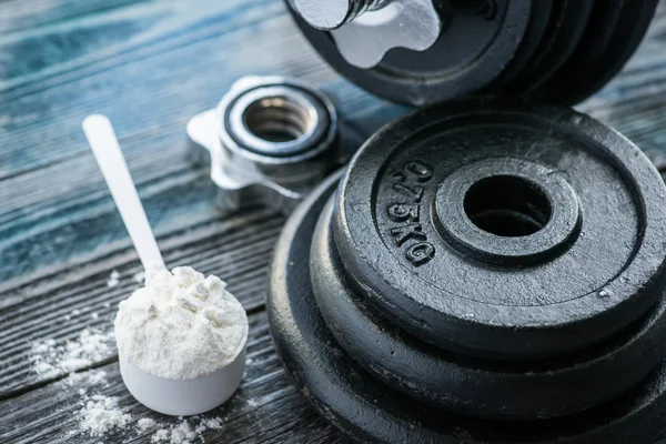 Protein tozu rustik ahşap masa üzerinde klasik halterle