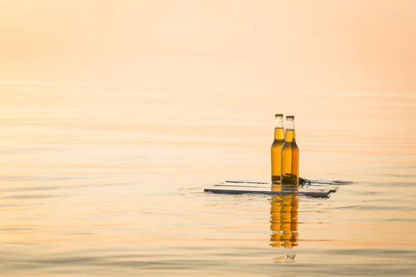 Ahşap tahta üzerinde yüzen bira şişeleri — Stok fotoğraf