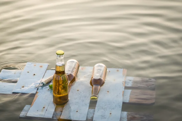 Pivní lahve plovoucí na dřevěné desce — Stock fotografie