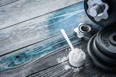 Protein tozu rustik ahşap masa üzerinde klasik halterle