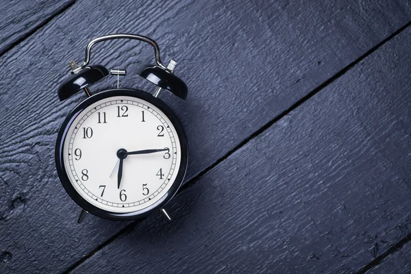 Vintage alarm clock on a black wooden surface — Stock Photo, Image