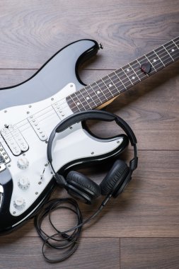 Elektro gitar kahverengi ahşap zemin üzerinde kulaklık ile