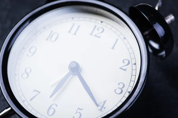 Alarm clock on a black wooden surface — Stock Photo, Image