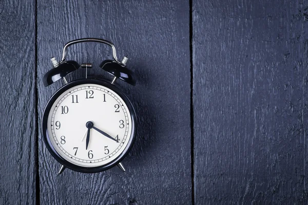 Alarm clock on a black wooden surface — Stock Photo, Image