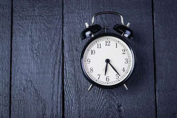 Alarm clock on a black wooden surface — Stock Photo, Image