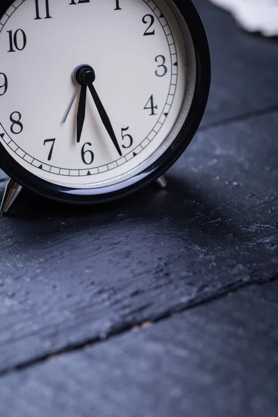 Reloj despertador sobre una superficie de madera negra — Foto de Stock