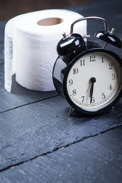 Wecker mit Toilettenpapier auf schwarzem Holztisch — Stockfoto