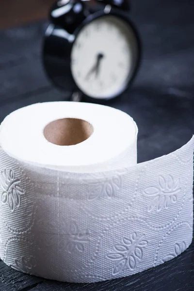 Wecker mit Toilettenpapier auf schwarzem Holztisch — Stockfoto