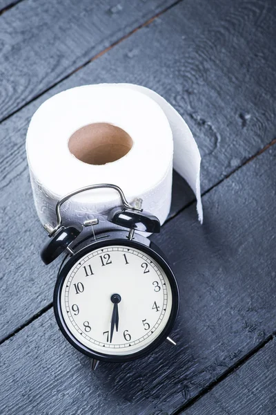 Wecker mit Toilettenpapier auf schwarzem Holztisch — Stockfoto