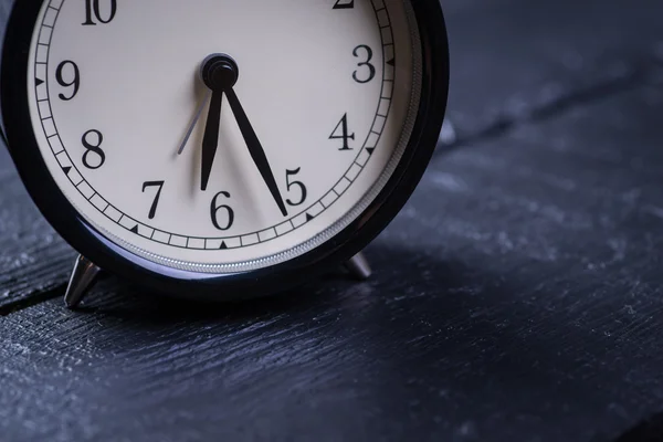 Reloj despertador sobre una superficie de madera negra — Foto de Stock