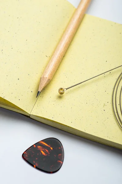 Yellow notepad with pencil, string and mediator on white surface — Stock Photo, Image