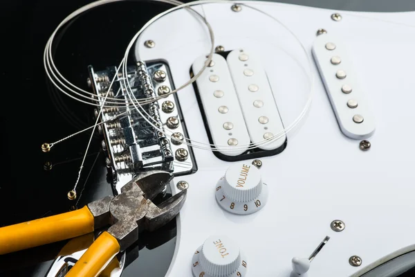 Electric guitar with yellow nippers and strings — Stock Photo, Image