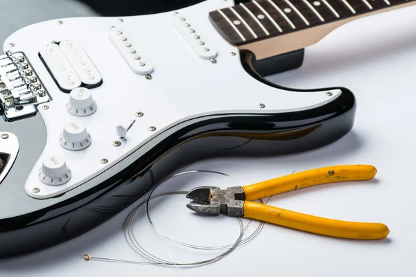 Electric guitar with yellow nippers and strings — Stock Photo, Image