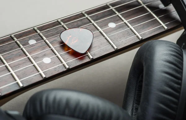 Electric guitar with headphones and mediator on a brown wooden floor — Stock Photo, Image