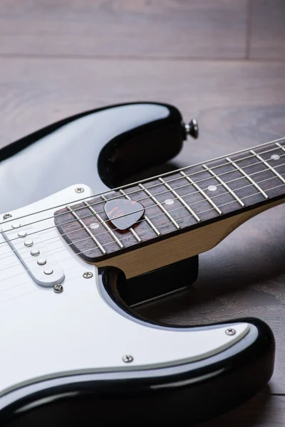 Electric guitar with mediator on a brown wooden floor — Stock Photo, Image