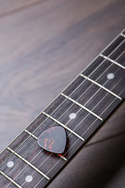 Trastes de guitarra con cuerdas y mediador en la superficie marrón oscuro —  Fotos de Stock