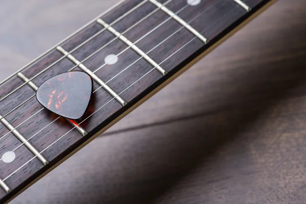 Trastes de guitarra con cuerdas y mediador en la superficie marrón oscuro — Foto de Stock