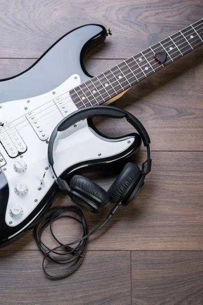 Electric guitar with headphones on a brown wooden floor — Stock Photo, Image