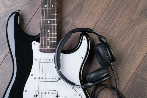 Electric guitar with headphones on a brown wooden floor — Stock Photo, Image