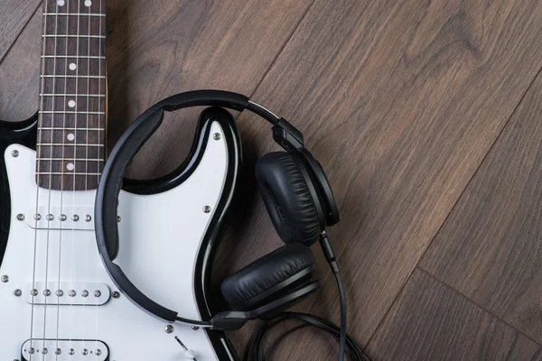 Electric guitar with headphones on a brown wooden floor — Stock Photo, Image