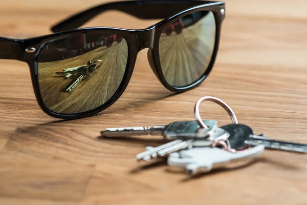 Schwarze Sonnenbrille mit Schlüsseln auf einem Holztisch — Stockfoto