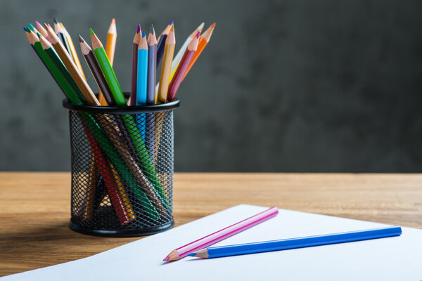 Bunch of color pencils with a white paper sheet